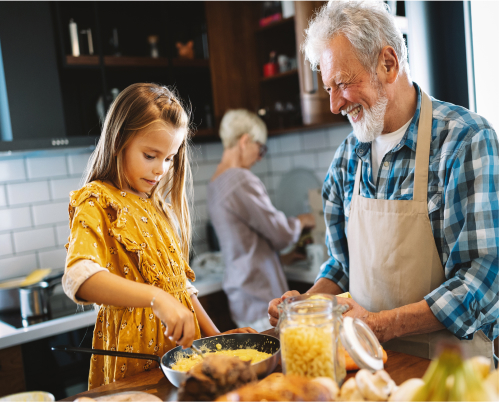 A grandma and grandpa cooking in the kitchen with a small girl